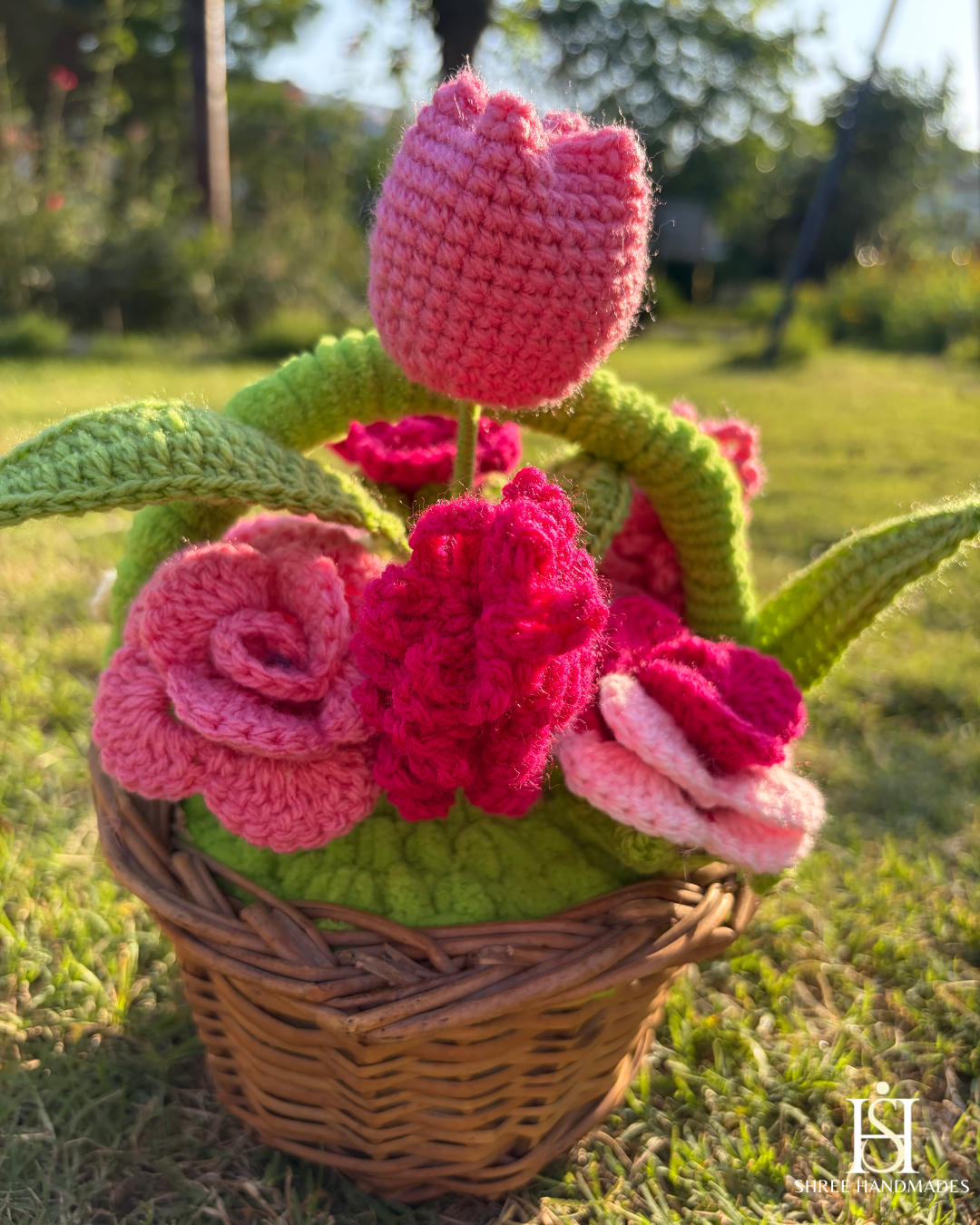 Crocheted pink mixed flowers in a wicker basket.