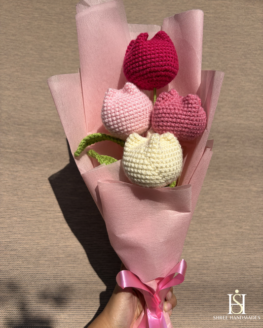 Bouquet of crocheted tulips in shades of pink and white wrapped in pink paper with a ribbon.